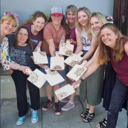 Teilnehmende eines BrandLinge Brandmalerei-Teamevents mit ihren selbst gestalteten Werkstücken.